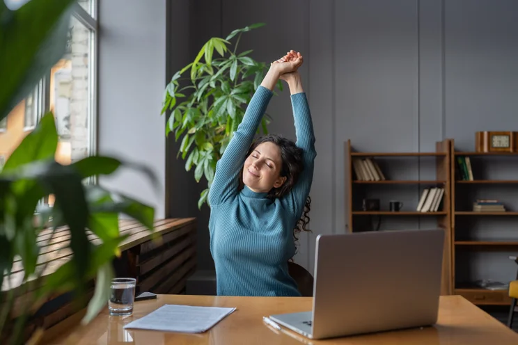 Woman stretching and looking happy at her desk