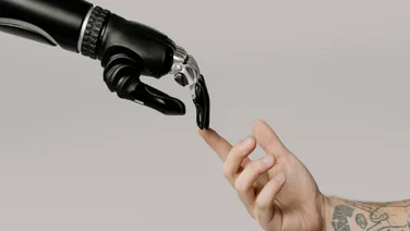 Robot and human hands touch to represent AI in the workplace.