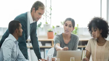 A group of employees working together around a laptop.