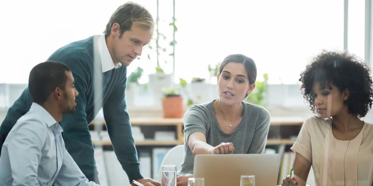 A group of employees working together around a laptop.