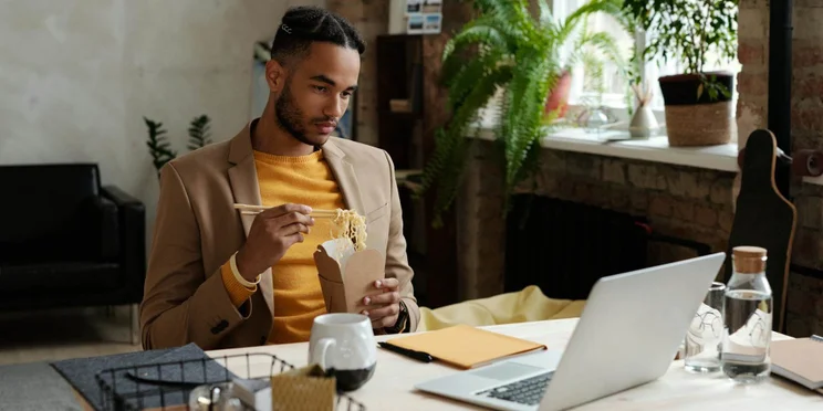 A remote worker eating in front of a laptop