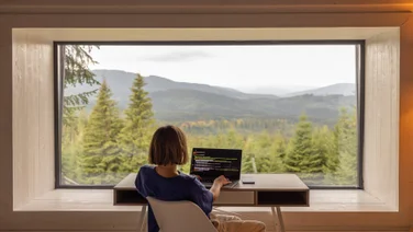 Woman working from home in front of a beautiful forest view