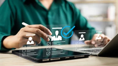 Person sat at laptop with superimposed graphic icons floating above an iPad.