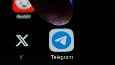 A person pressing the telegram app on their phone.