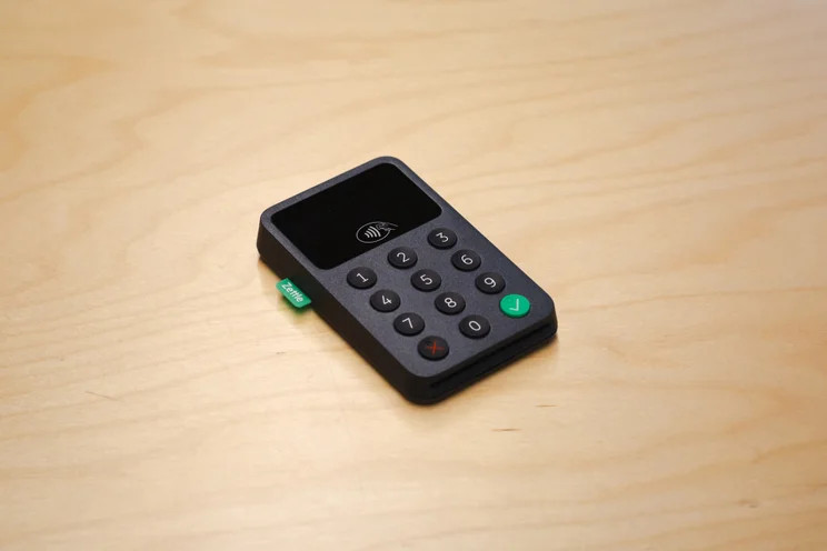 Black Zettle card reader with touchscreen display on wooden surface.