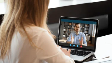 A video interview being conducted by a woman with a laptop.
