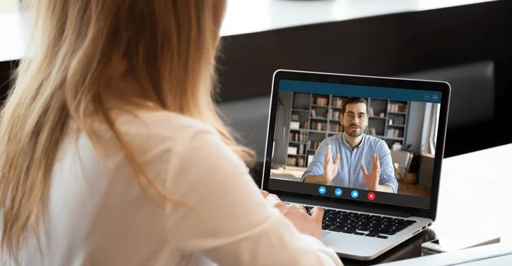 A video interview being conducted by a woman with a laptop.