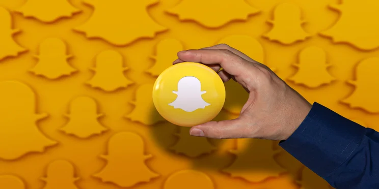 A man holding an orb displaying the snapchat logo.