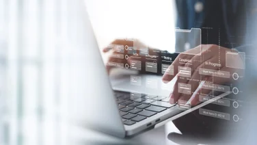 Person typing on keyboard with project management software on display