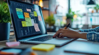 Person typing on laptop with post-it notes on screen