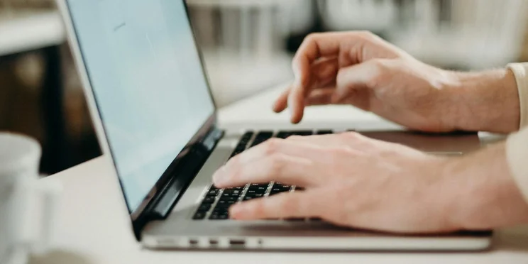 Hands typing on a laptop