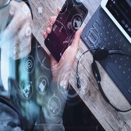 Person on mobile with laptop in background
