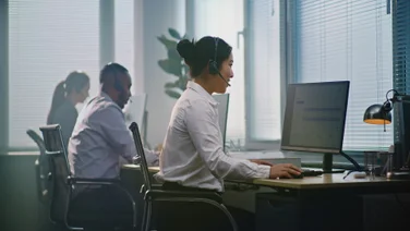People working in an office, talking on headsets