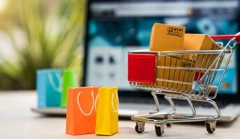 small shopping cart graphic with bags and laptop in background