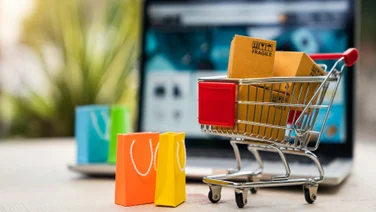 small shopping cart graphic with bags and laptop in background