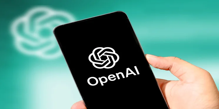 Person holding phone with OpenAI on screen