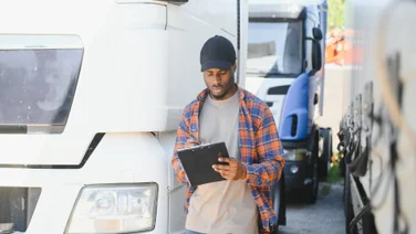 Man looking at clipboard assessing trucks
