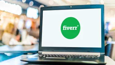 Fiverr logo on open laptop with busy background