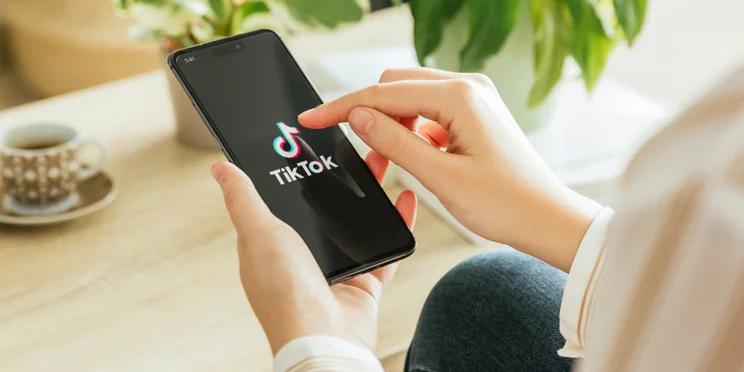 Person holding phone with TikTok logo