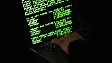 Someone types code on a computer in the dark