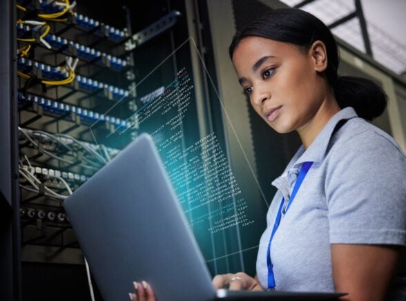 Woman on laptop next to electronics panel