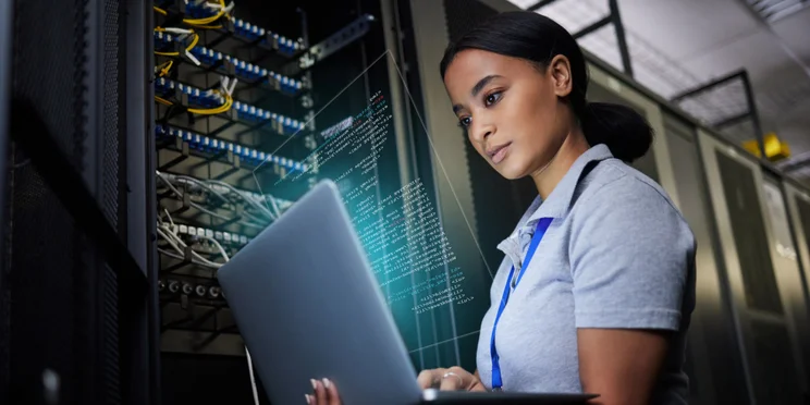 Woman on laptop next to electronics panel