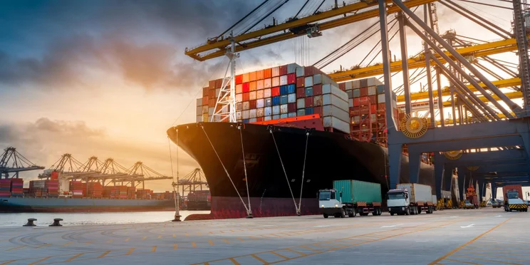 Shipping containers on a truck near a ship