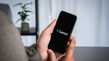Person holding phone with Google Gemini logo on black screen
