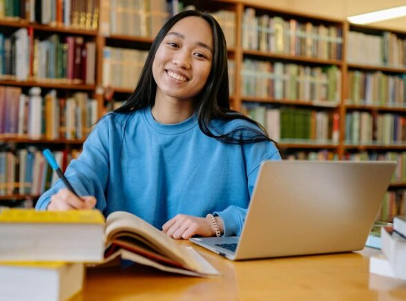 Woman with books and laptop in a library