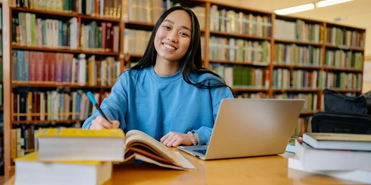 Woman with books and laptop in a library