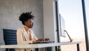Woman at desk using computer next to window