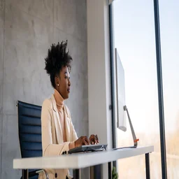 Woman at desk using computer next to window