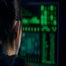 Cyberhacker looks at green text on a computer