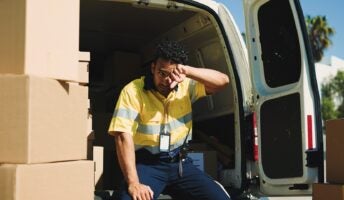 Delivery driver on back of van exhausted with boxes
