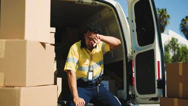 Delivery driver on back of van exhausted with boxes