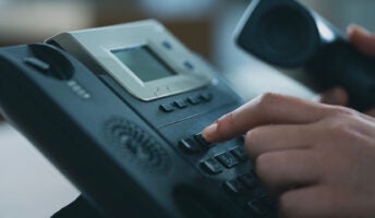 Person typing on VoIP desk phone