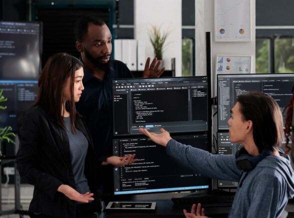 Employees surrounding computer in modern office