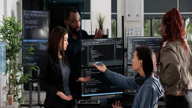 Employees surrounding computer in modern office