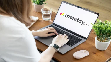 Person working on laptop with monday.com logo on screen