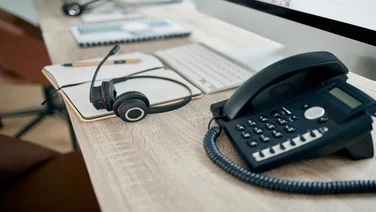 VoIP deskphone next to headset on office desk