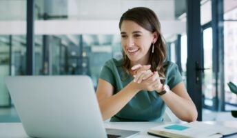Worker in office smiling at laptop