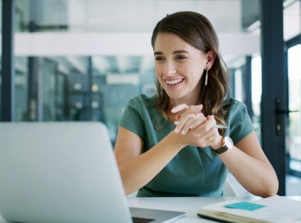 Worker in office smiling at laptop