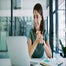 Worker in office smiling at laptop