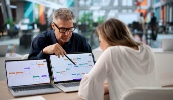 Business professionals collaborating over laptop screens