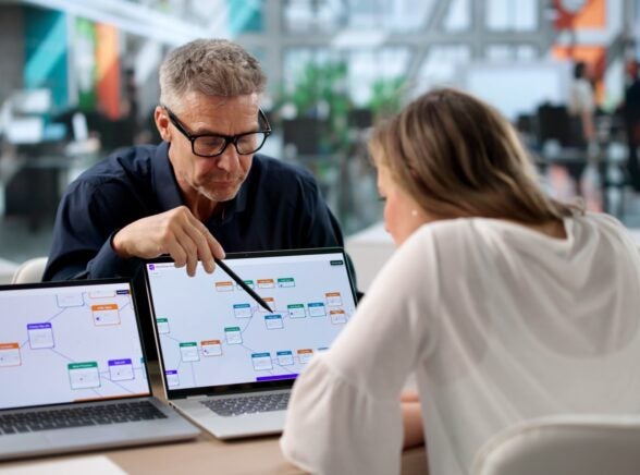 Business professionals collaborating over laptop screens