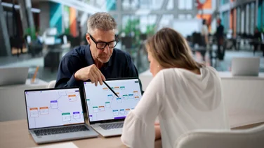 Business professionals collaborating over laptop screens