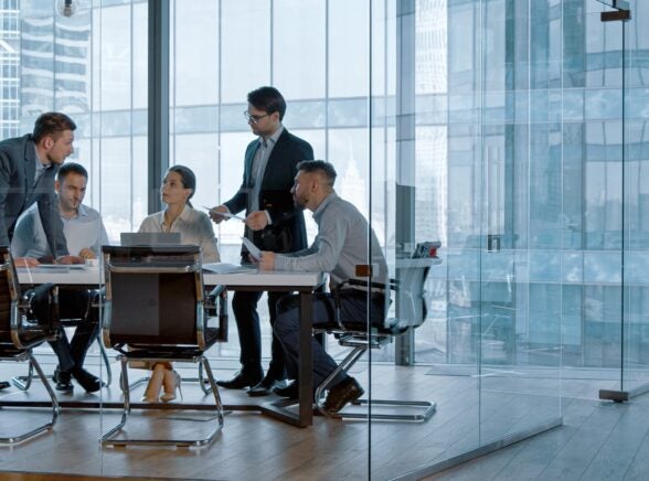 Workers in glass office collaborating