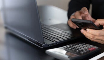 Person working out payroll with calculator and laptop