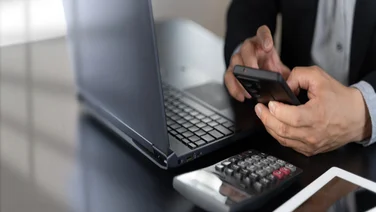 Person working out payroll with calculator and laptop
