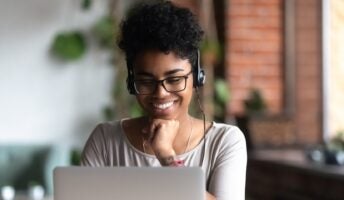 Worker on laptop smiling in office
